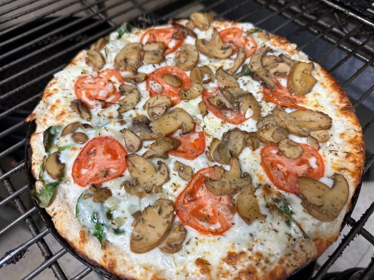 A savory grilled pizza topped with mushrooms, tomatoes, and spinach